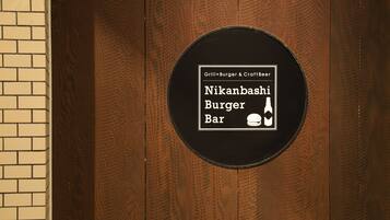 Un cartell a una porta de fusta anuncia Nikanshahi Burger Bar, amb servei de plats a la planxa, hamburgueses i cervesa artesana.