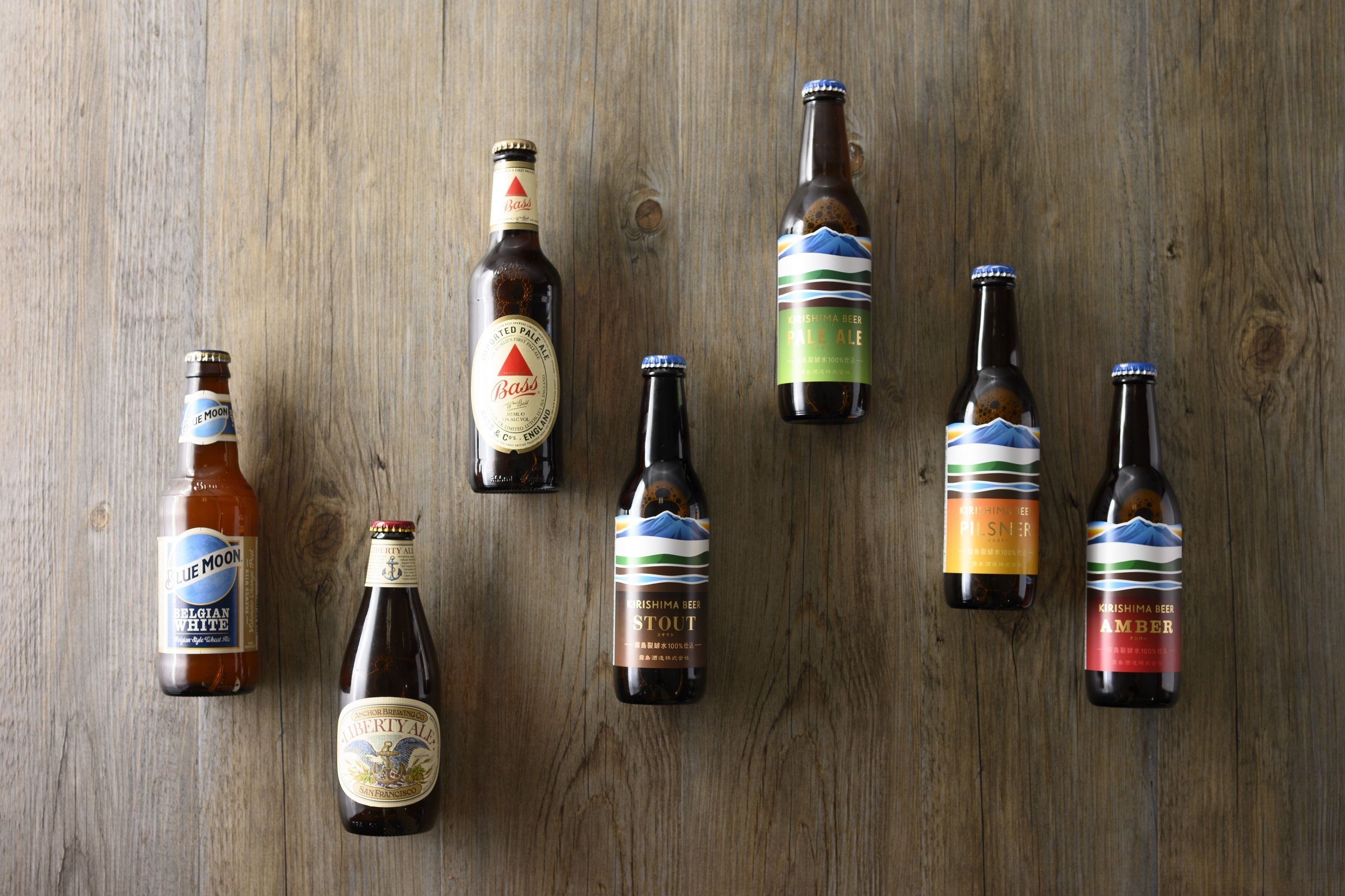 Sete garrafas de cerveja dispostas sobre uma superfície de madeira.