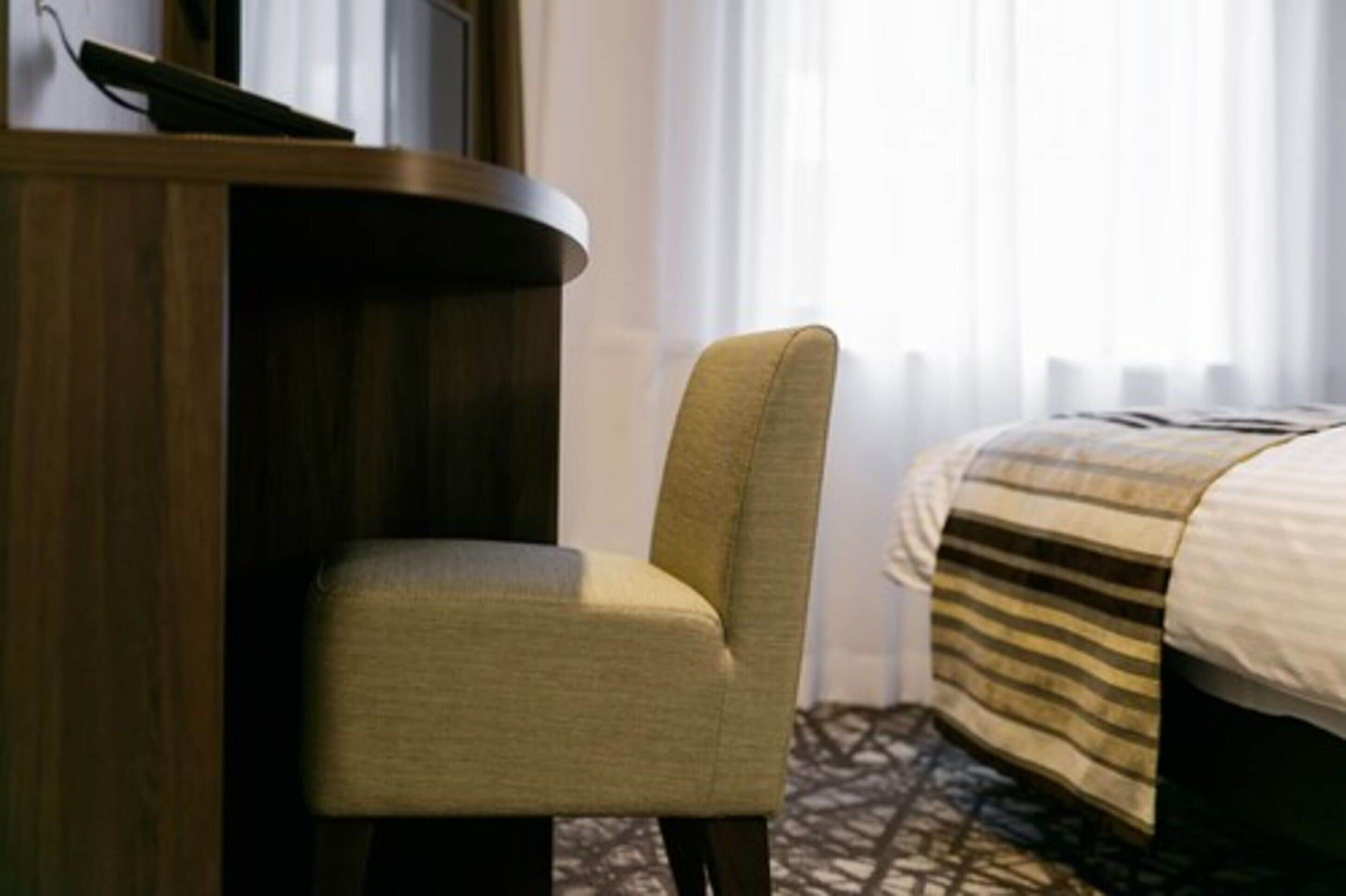 A hotel room with a bed, a wooden desk, and a chair.