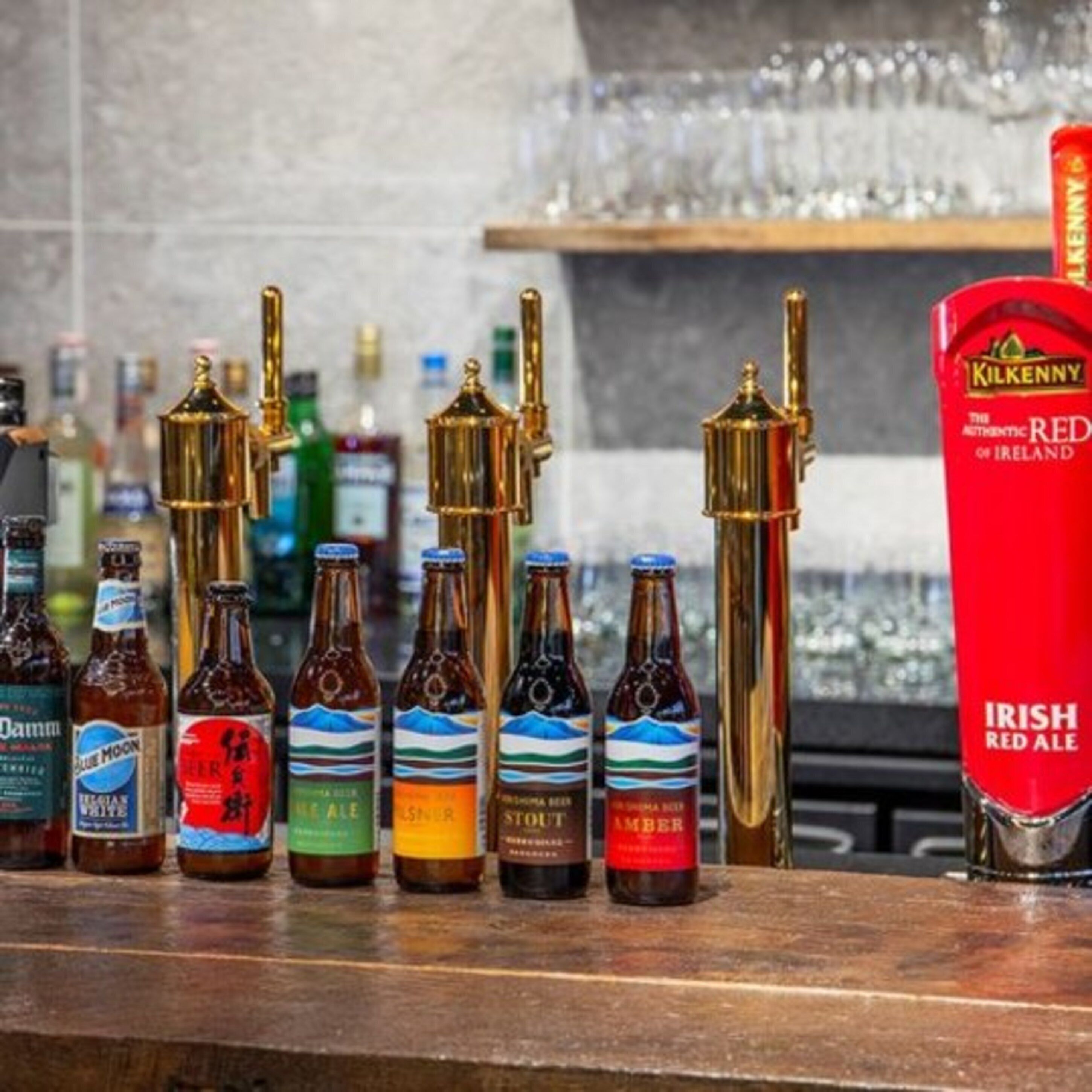 A bar with various bottles of beer and a red tap labeled "Irish Red Ale".