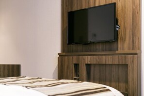 A modern hotel room with a large bed, a mounted flat-screen TV, and wooden paneling on the walls.