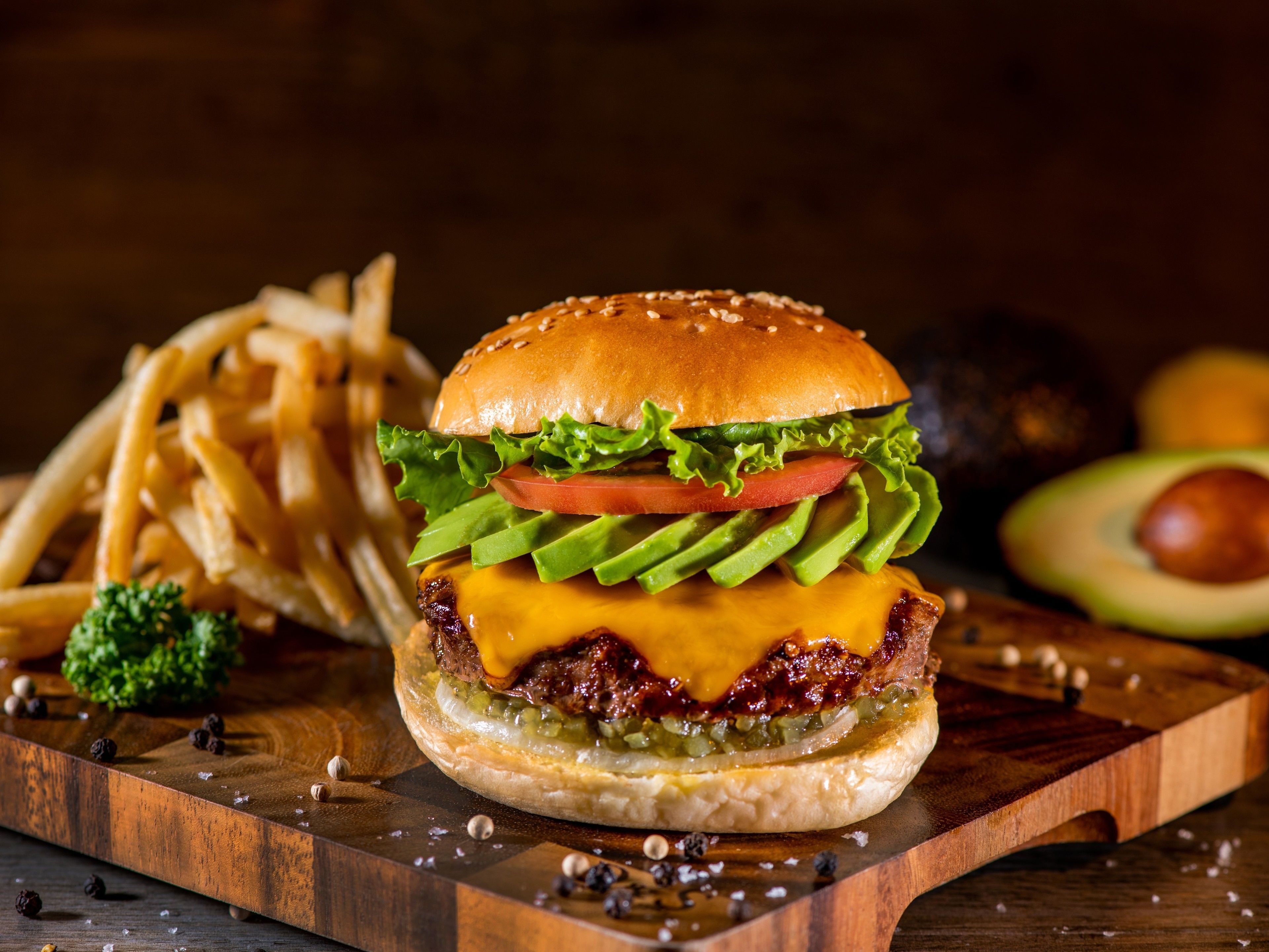 A burger with fries on a wooden board.