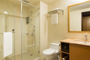 Un baño moderno con ducha envuelta en vidrio, inodoro y tocador con lavamanos.