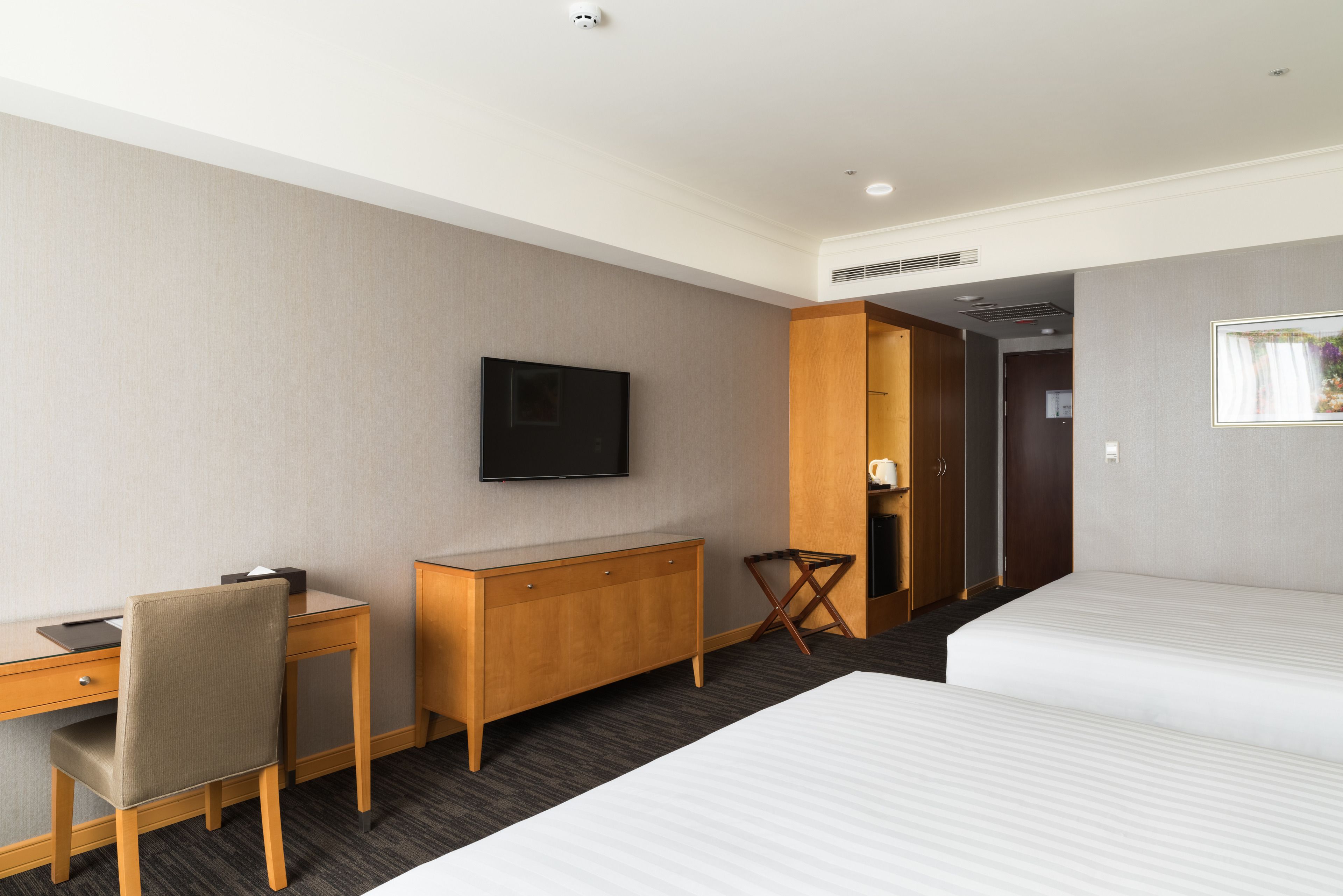 Una habitación de hotel con una cama, un escritorio, una silla, un televisor y un armario.