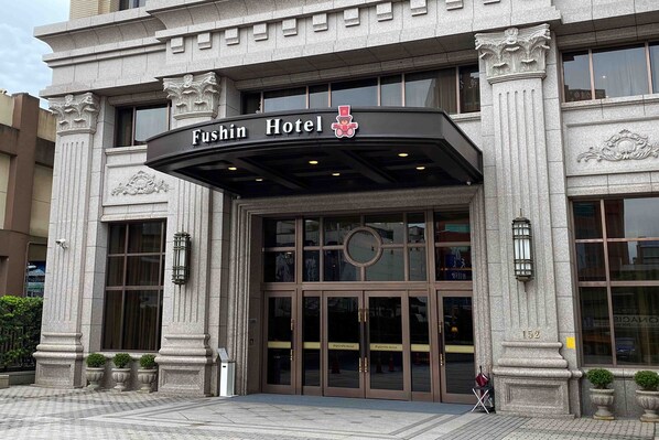 Entrada del Hotel Fushin con arquitectura clásica, incluyendo columnas y molduras decorativas.