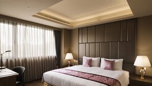 Ein Hotelzimmer mit einem großen Bett, zwei Nachttischen mit Lampen, einem Schreibtisch und einem Stuhl.