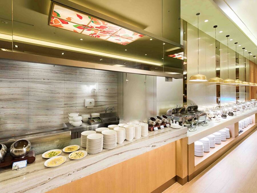 A modern buffet setup with a marble countertop, stainless steel appliances, and a variety of dishes and utensils.