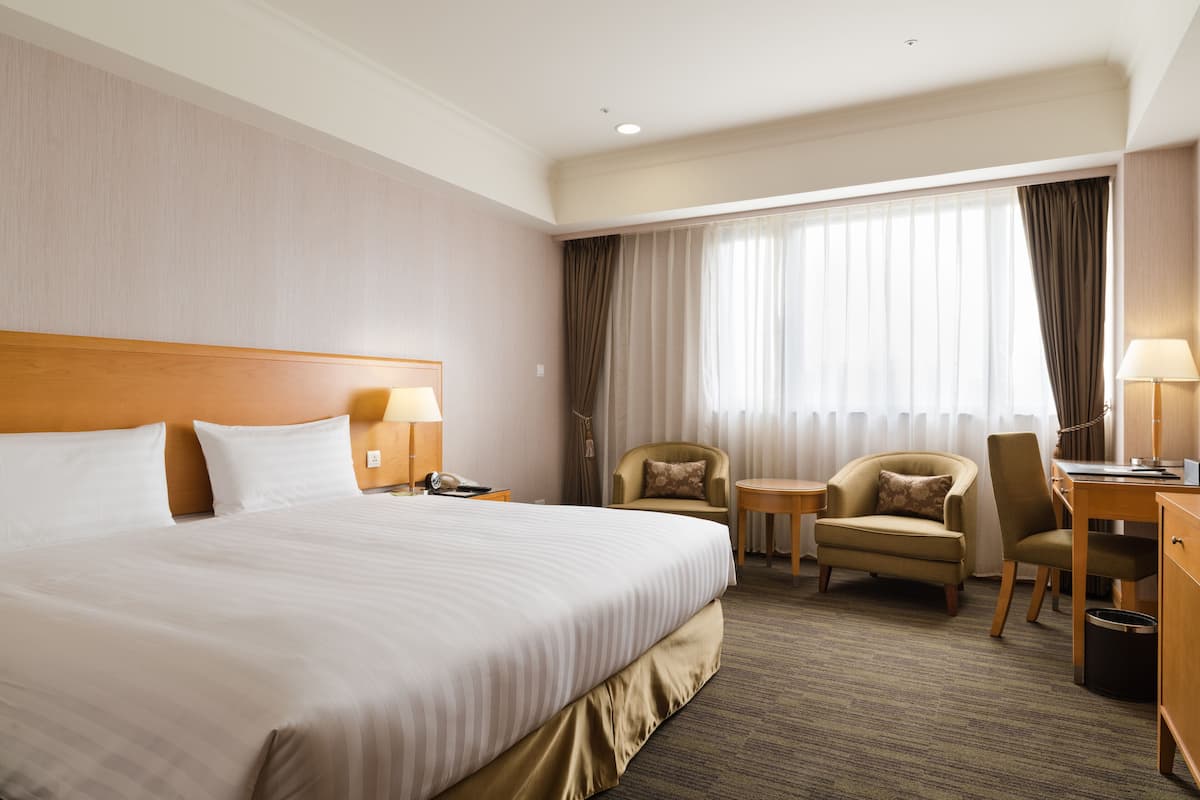 Una habitación de hotel con una cama grande, dos sillas, un escritorio y una mesita.