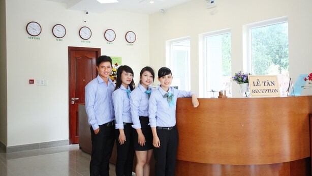 A reception area with a wooden reception desk, clocks on the wall, and a sign reading "LE TAN RECEPTION". - Sun and Sea Hotel Phu Quoc (Phu Quoc)