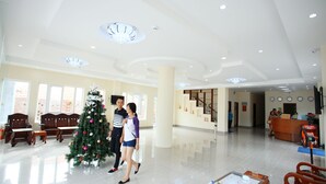 A spacious lobby with a Christmas tree, wooden furniture, and a reception desk.