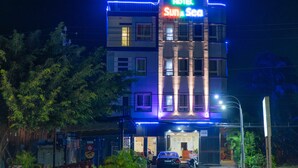 A multi-story hotel with a neon sign reading "HOTEL Sun & Sea" and a contact number.