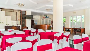 A hotel reception area with a reception desk, a clock, and a wall with the hotel's name.