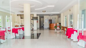 A hotel lobby with a reception desk, a staircase, and a reception area with a clock and a sign.