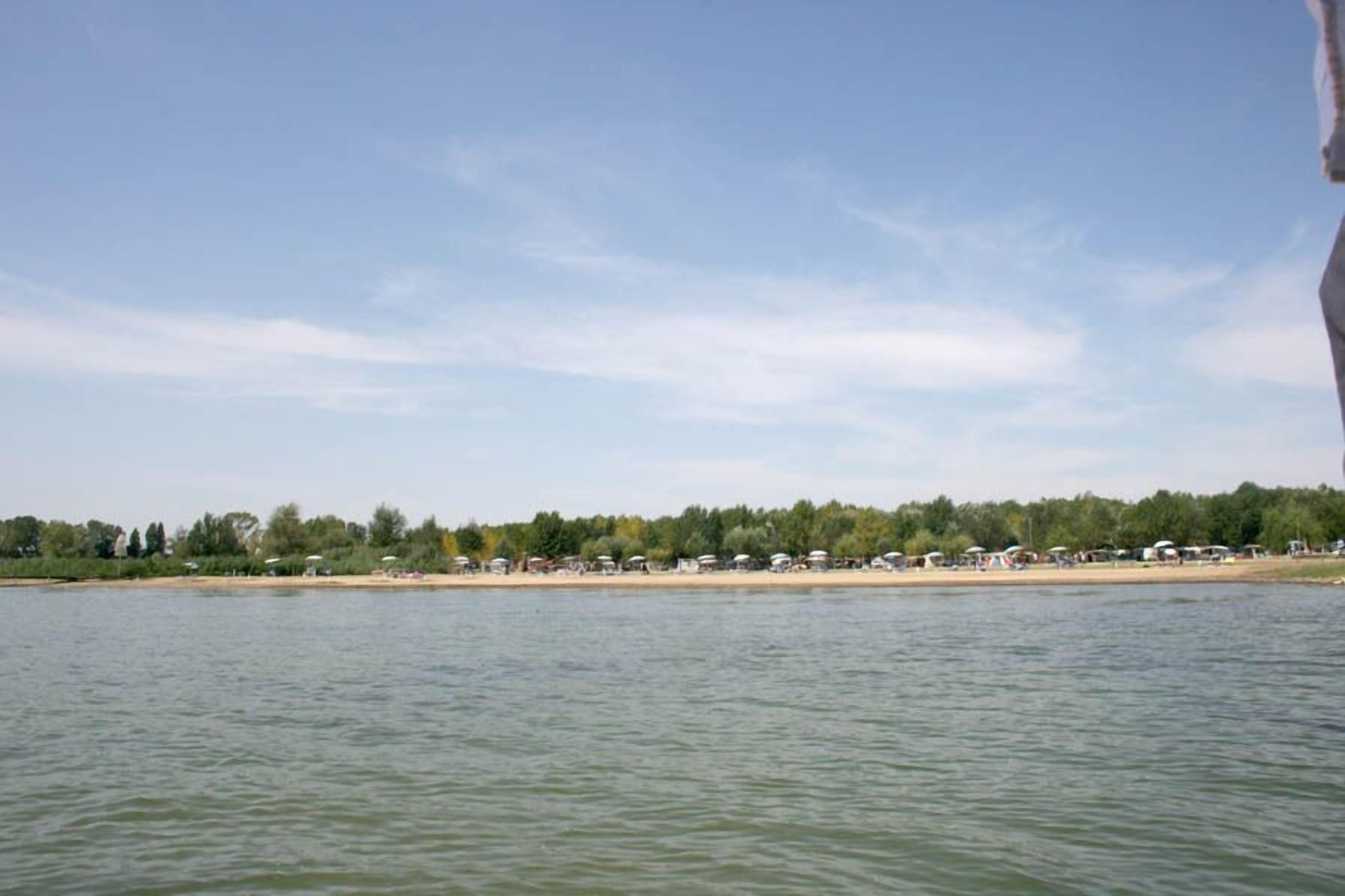A calm lake with a row of beachside cottages and a forested area in the background.