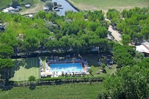 An aerial view of a resort with a swimming pool, tennis courts, and lush greenery.