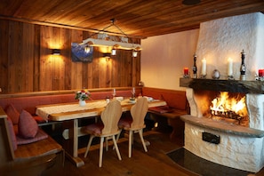 A cozy dining area with wooden walls, a stone fireplace, and a wooden table with benches.