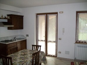 Una cocina funcional con mesa, armarios de madera y ventana con cortinas.