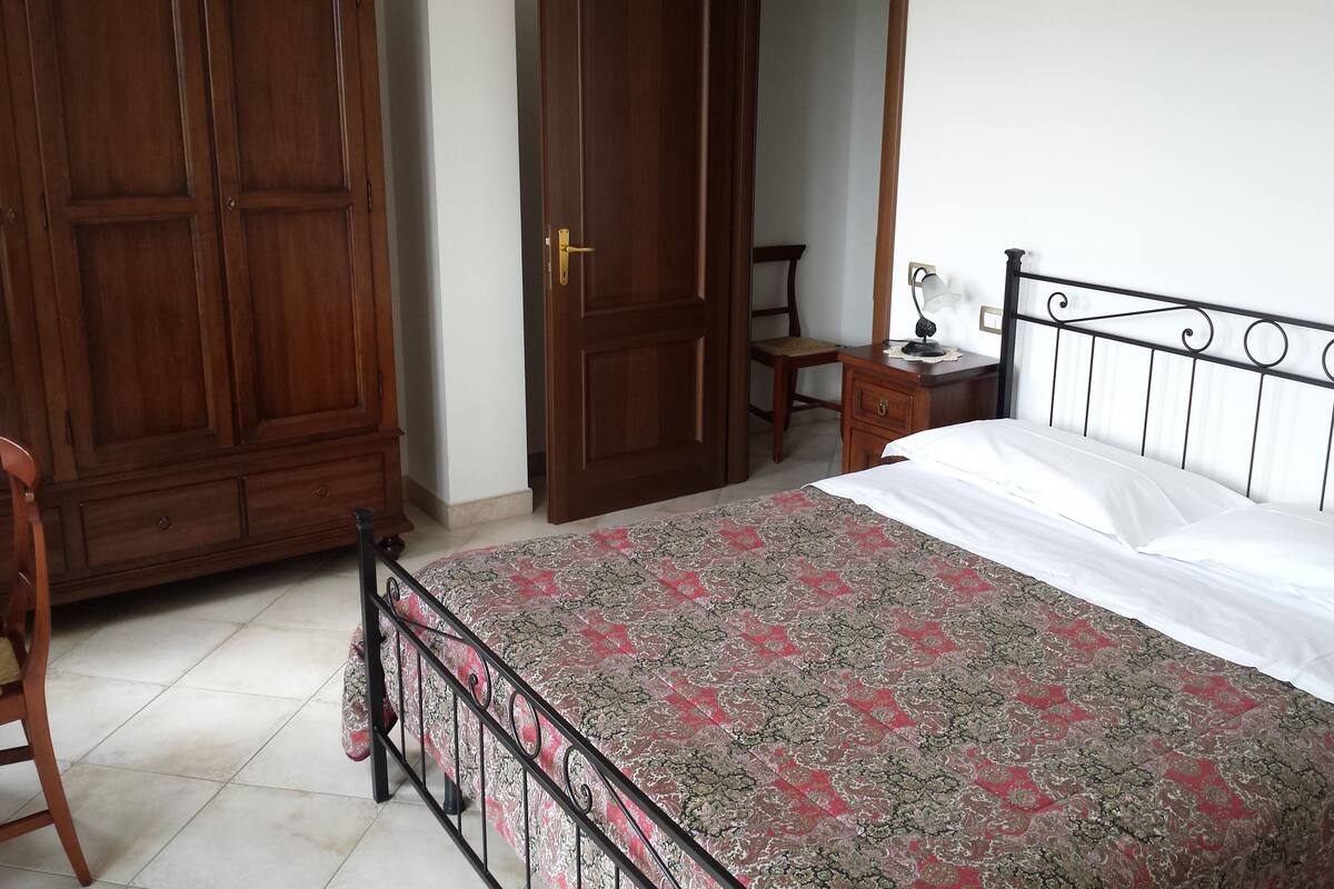 Ein Schlafzimmer mit Bett, Holzschrank und Schreibtisch mit Stuhl.