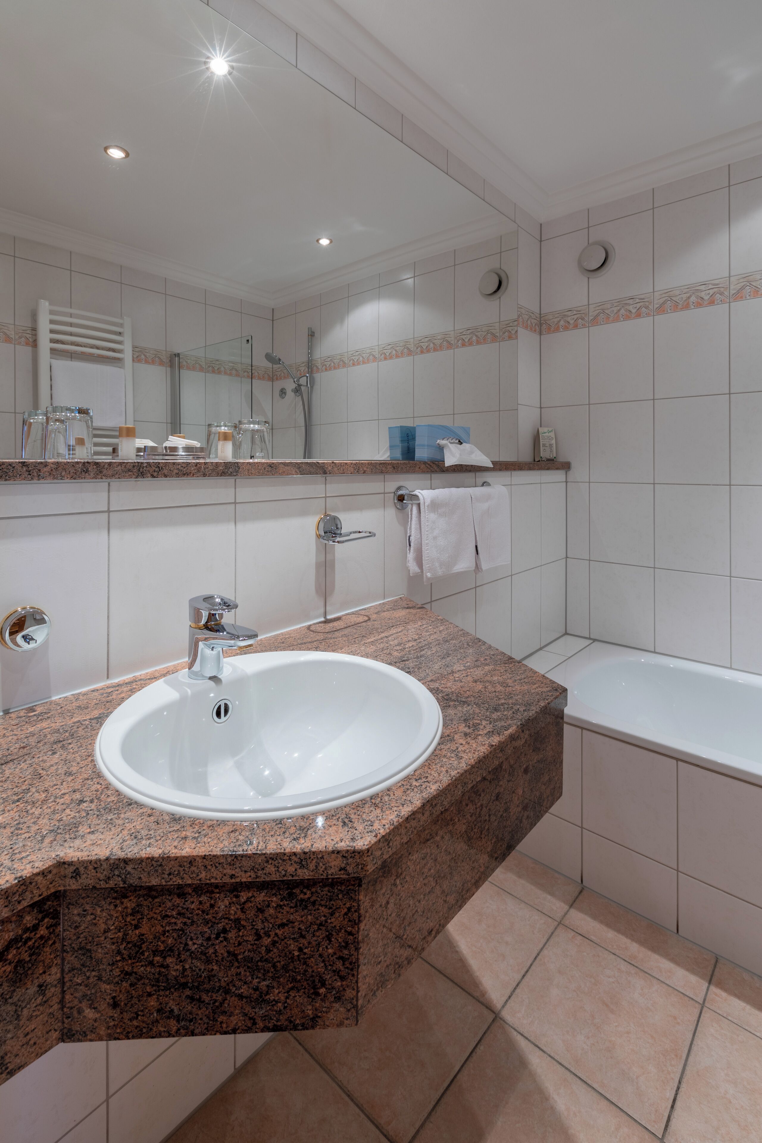 Un baño moderno con lavamanos de granito, un espejo, ducha y bañera.