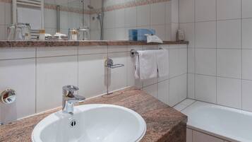 A modern bathroom with a granite countertop sink, a mirror, a shower, and a bathtub.