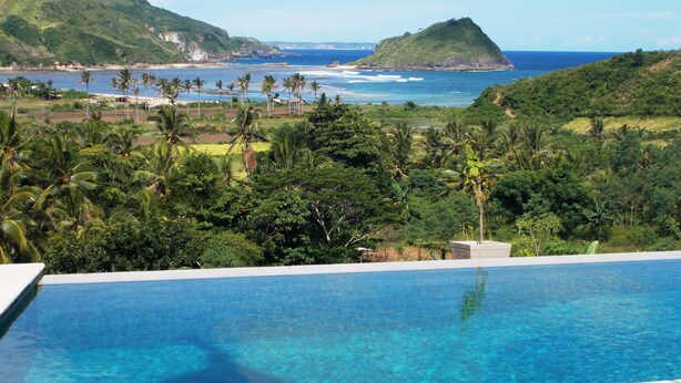 A pool with a view of the ocean and a hill in the background. - Blue Monkey Villas Resort & Ocean View (Kuta)