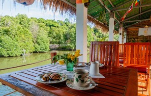 A wooden table with a plate of food, a cup, and a vase of flowers. - Spayhiti (Sihanoukville)
