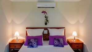 A hotel room with a bed, two nightstands, a wall-mounted air conditioner, and a potted plant. - Spayhiti (Sihanoukville)