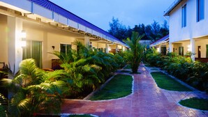 A hotel corridor with multiple rooms on either side, a central pathway, and lush tropical plants. - Spayhiti (Sihanoukville)