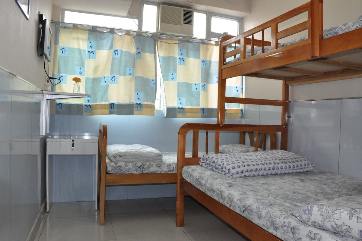 Habitación con literas, escritorio y ventana con cortinas.