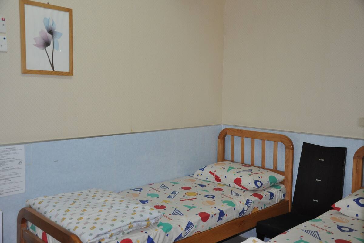 Una cama individual con una colcha de colores y diseño, un cabecero de madera y un cuadro en la pared.