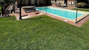 A pool area with a stone building, a hot tub, and lounge chairs. - Agriturismo Ripaiani (Marsciano)