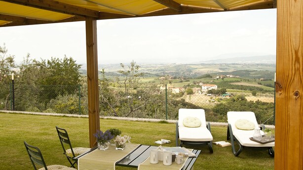 A covered outdoor seating area with a table set for two, overlooking a scenic landscape. - Agriturismo Ripaiani (Marsciano)