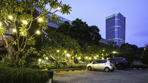 Een parkeerplaats met twee auto's, omgeven door bomen en verlicht door straatverlichting.