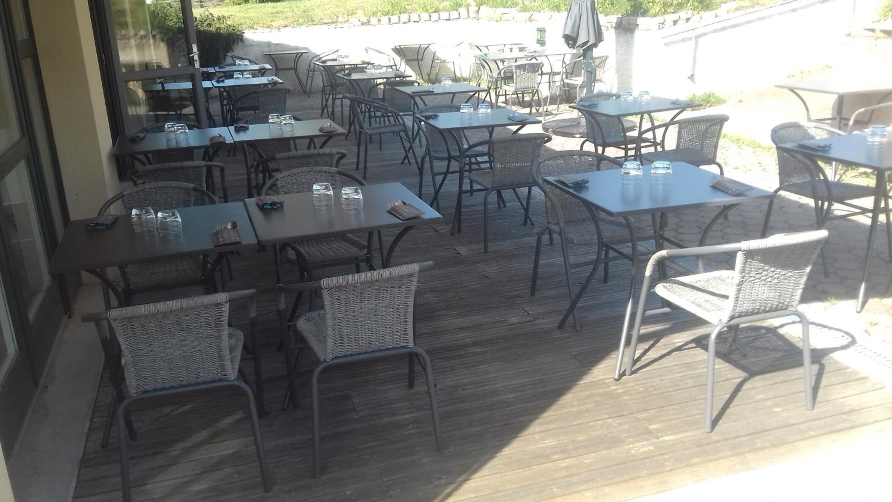 An outdoor patio area with multiple tables and wicker chairs.
