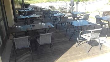 An outdoor patio area with multiple tables and wicker chairs.
