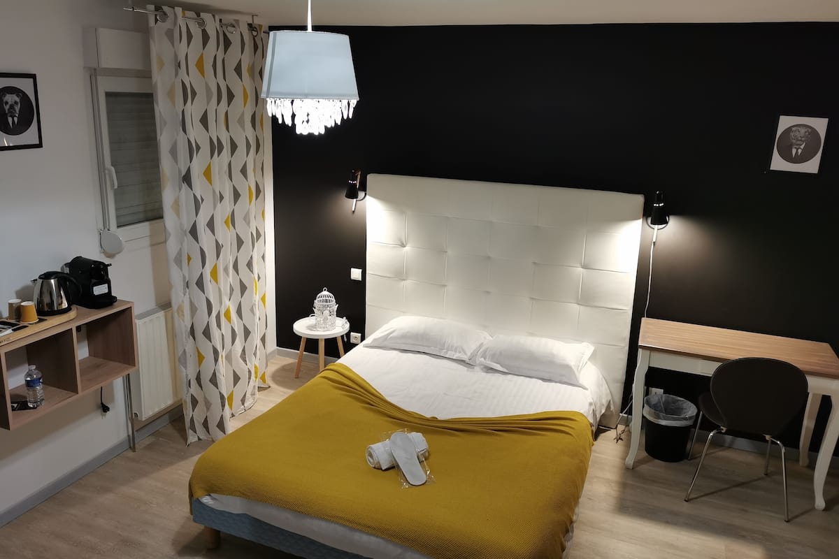 Quarto bem organizado com cama, mesa de cabeceira e escrivaninha.