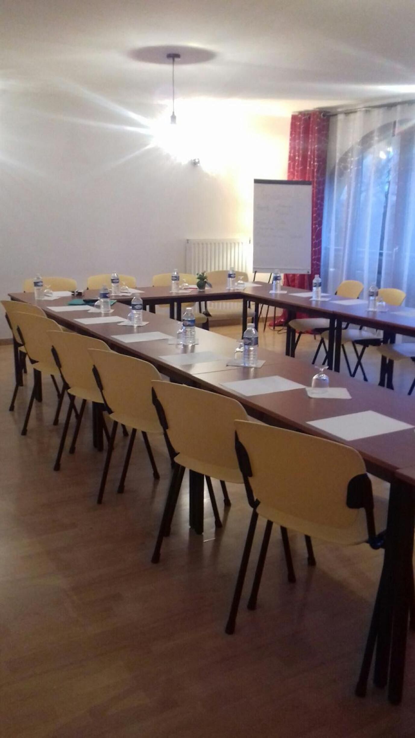 A conference room with a long table, yellow chairs, water bottles, and a whiteboard.