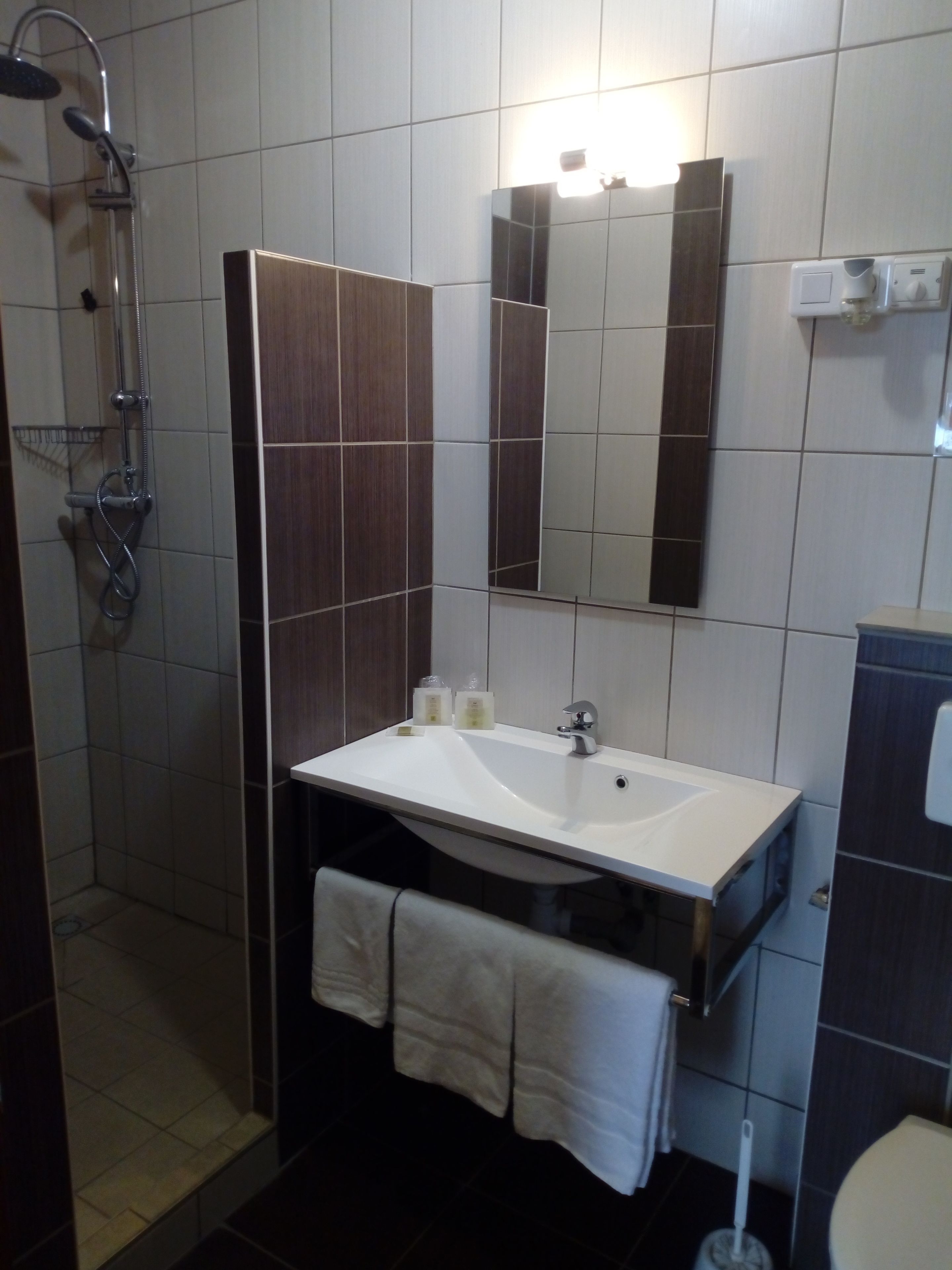 Ein Badezimmer mit Waschbecken, Spiegel, Handtuch und Dusche.