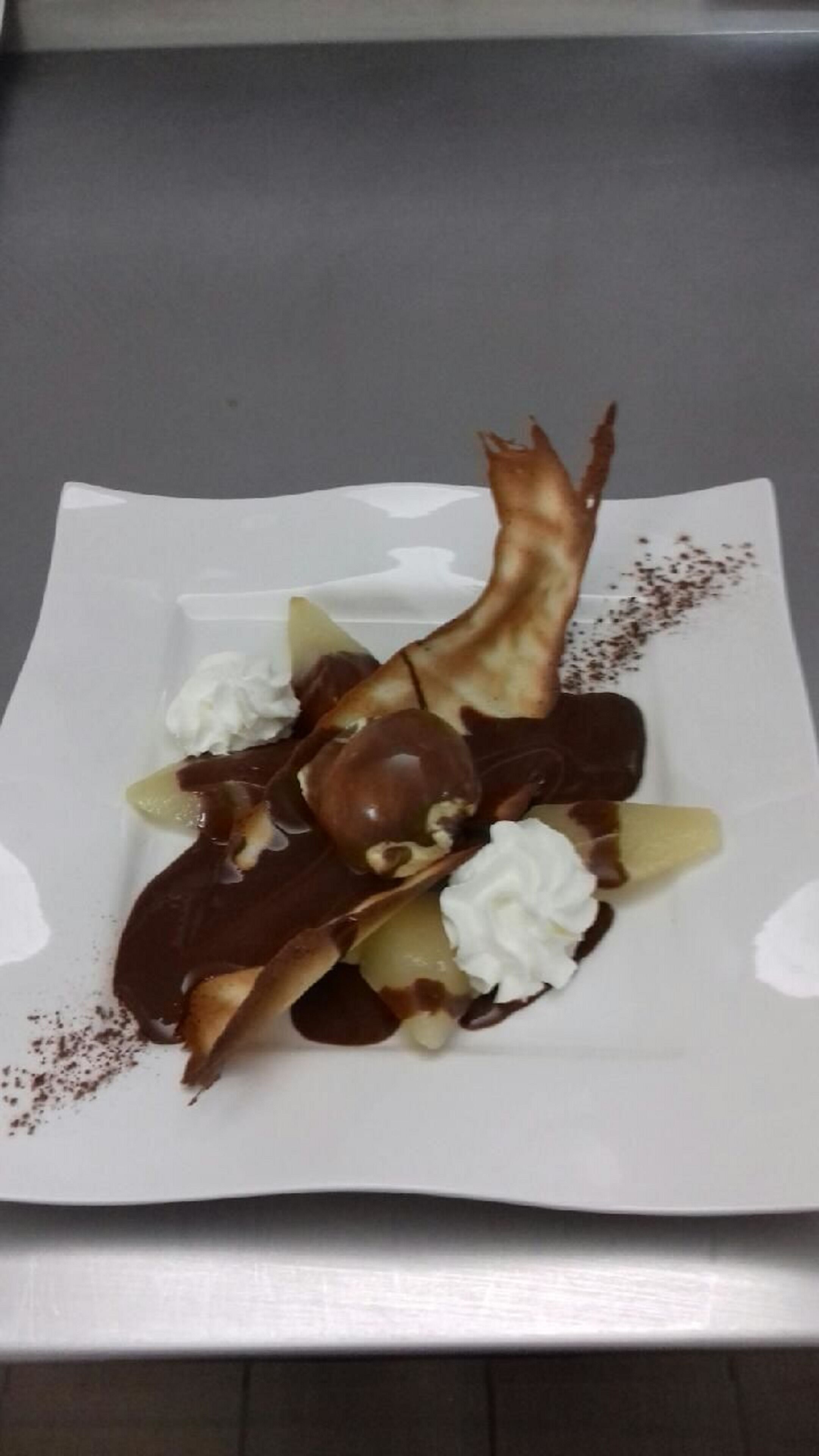 Une assiette de dessert comprenant de la sauce au chocolat, de la crème fouettée et une pâtisserie.