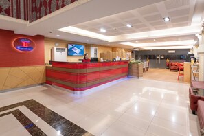 Et hotelreceptionsskrank med en digital skærm, et ur og en bordplade i rødt og sølv.