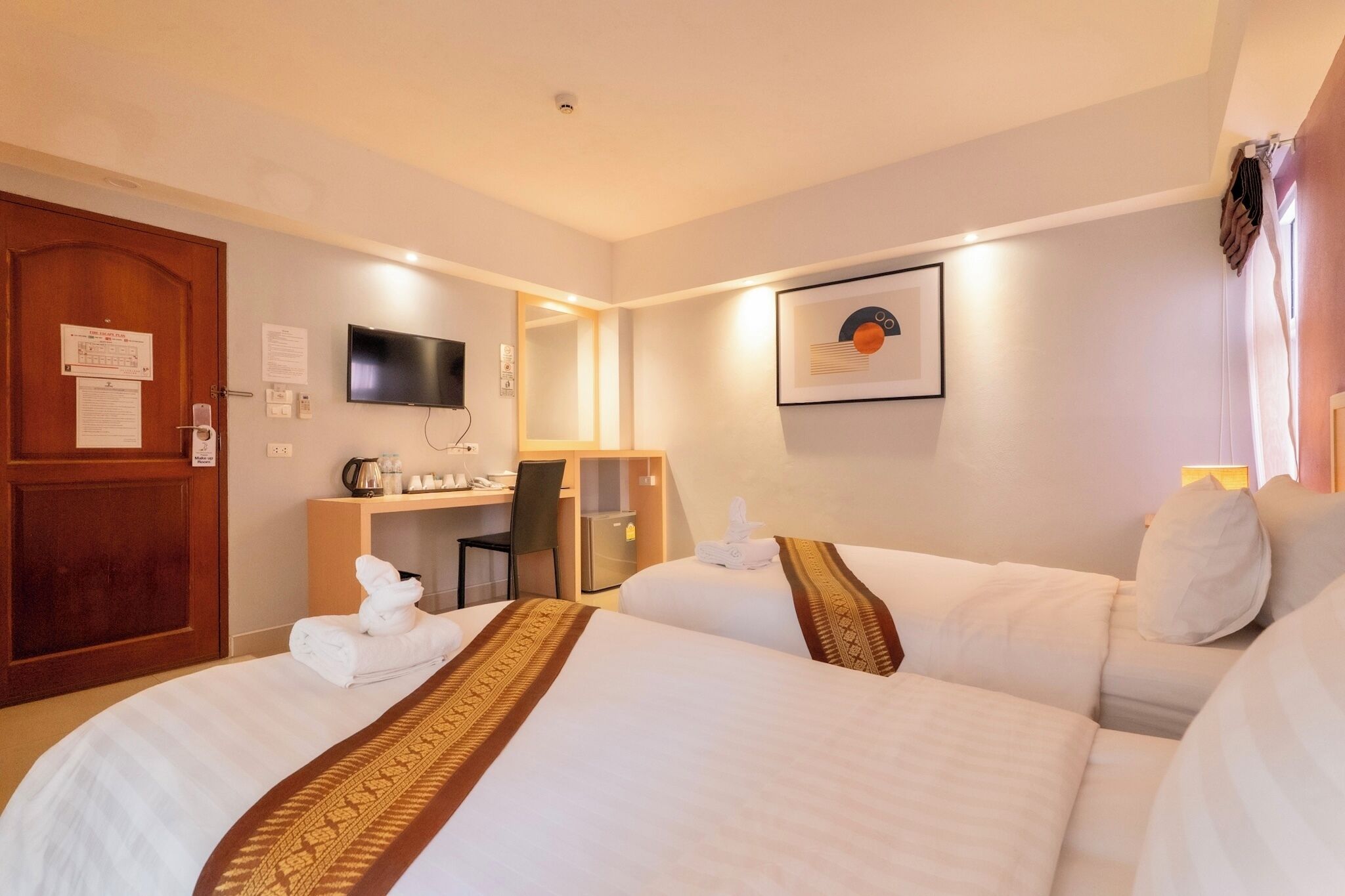 Habitación de hotel con dos camas, un escritorio, un televisor y un cuadro en la pared.