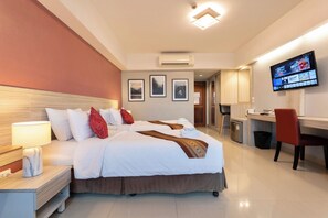 A hotel room with a bed, bedside table, TV, and a desk area. - Tubtim Siam Suvarnabhumi Hotel (Bang Phli)
