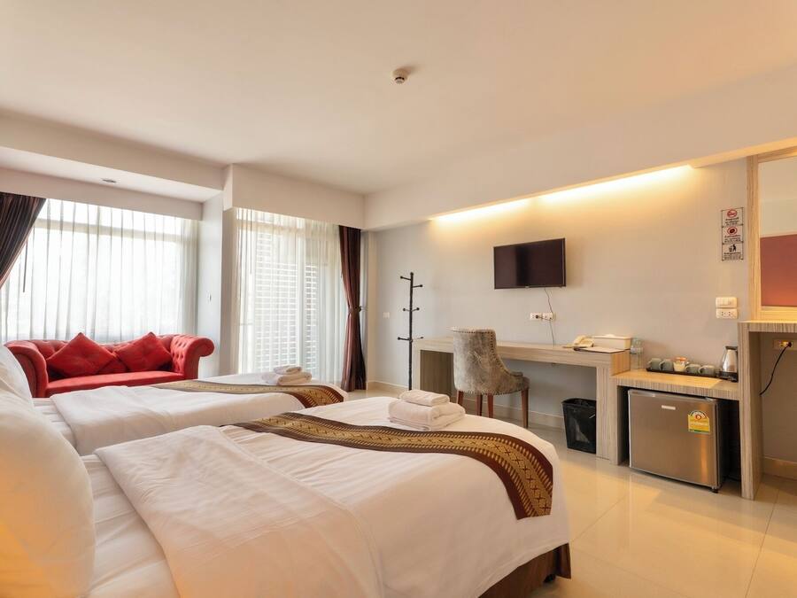 Habitació d'hotel amb dos llits, escriptori, cadira, televisió i minibar.