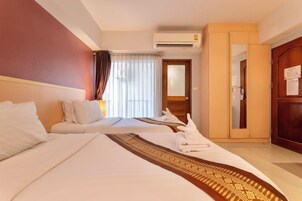 Una habitación de hotel con dos camas, un armario, un equipo de aire acondicionado y una puerta con espejo.