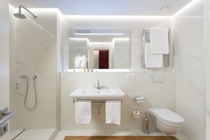 Et moderne badeværelse med bruser, håndvask og toilet.