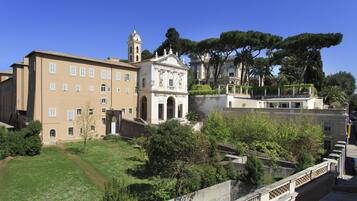 A historic building with a bell tower, surrounded by lush greenery and other structures.