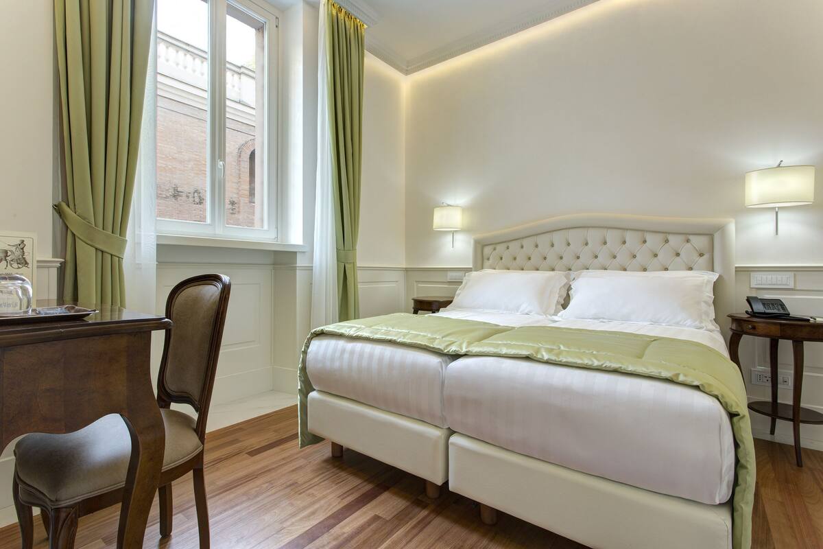 A neatly arranged bedroom with a large bed, a wooden desk, and a chair.