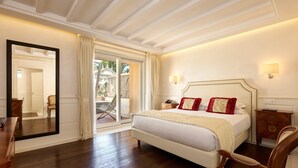 A well-lit bedroom with a large bed, a mirror, a nightstand, and a view of the outdoors through a sliding door. - Hotel degli Artisti (Rome)