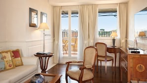 A hotel room with a sofa, two chairs, a desk, and a view of the outdoors through large windows. - Hotel degli Artisti (Rome)