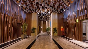 A hallway with a geometric patterned ceiling, wooden paneling on the walls, and a marble floor. -  The Malibu Hotel (Ho Chi Minh City)